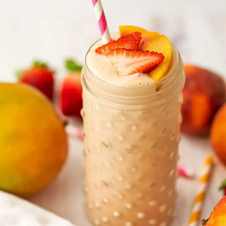 Strawberry mango peach smoothie topped with sliced strawberries and peaches.