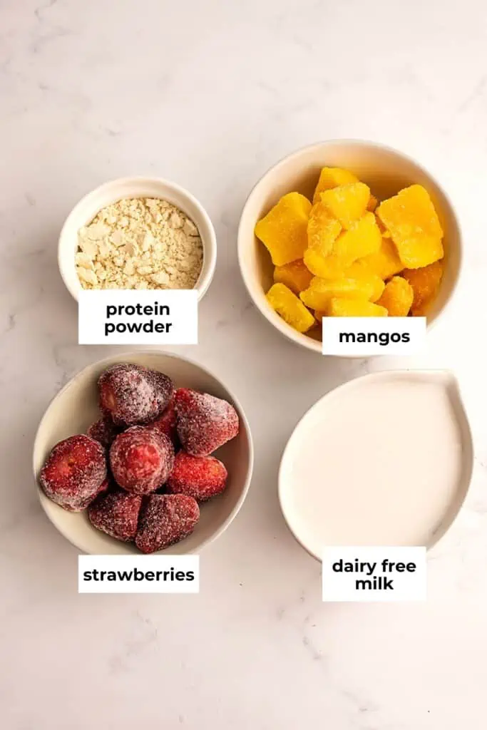 Strawberry mango smoothie bowl ingredients in white ramekins.