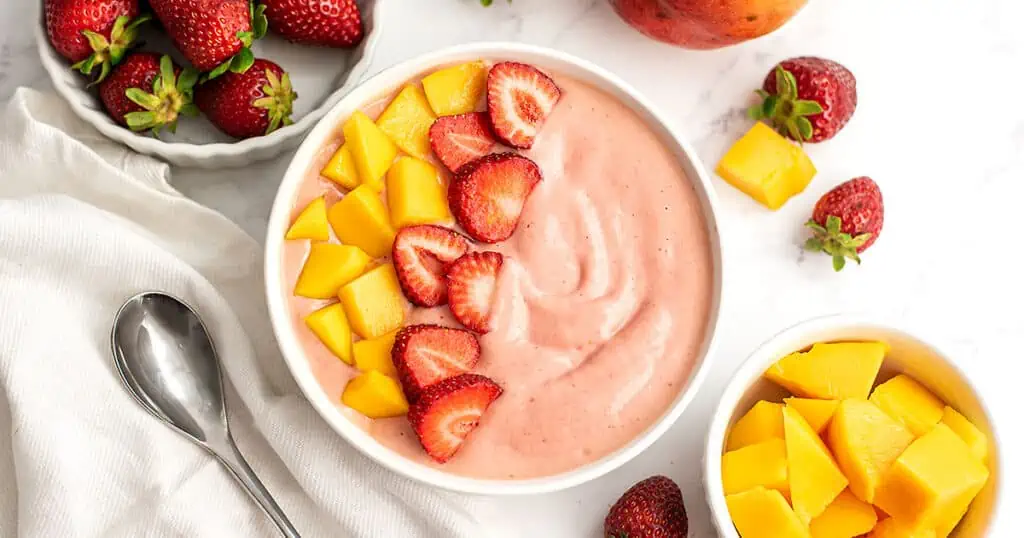 Strawberry mango smoothie bowl with sliced strawberries and mangos on top.