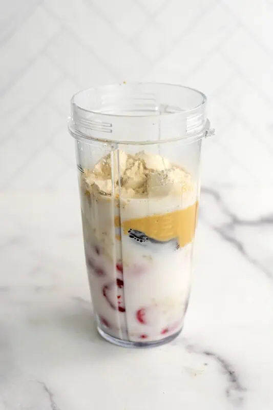 Strawberry smoothie no banana ingredients in a blender cup before blending.