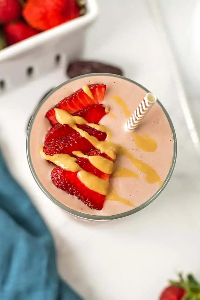 Strawberry smoothie no banana with tahini drizzle and sliced strawberries on top.