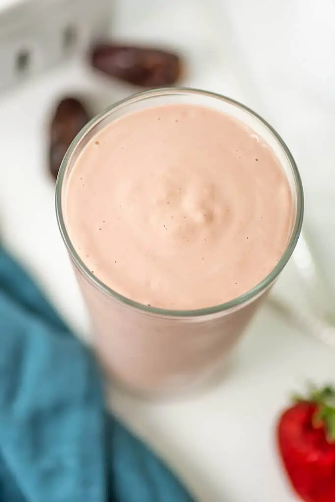 Strawberry tahini smoothie in a tall glass with no toppings.