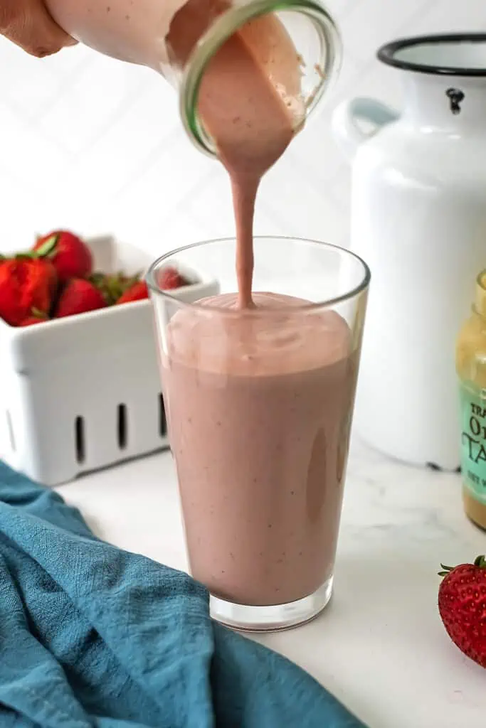 Strawberry tahini smoothie being poured into a glass.