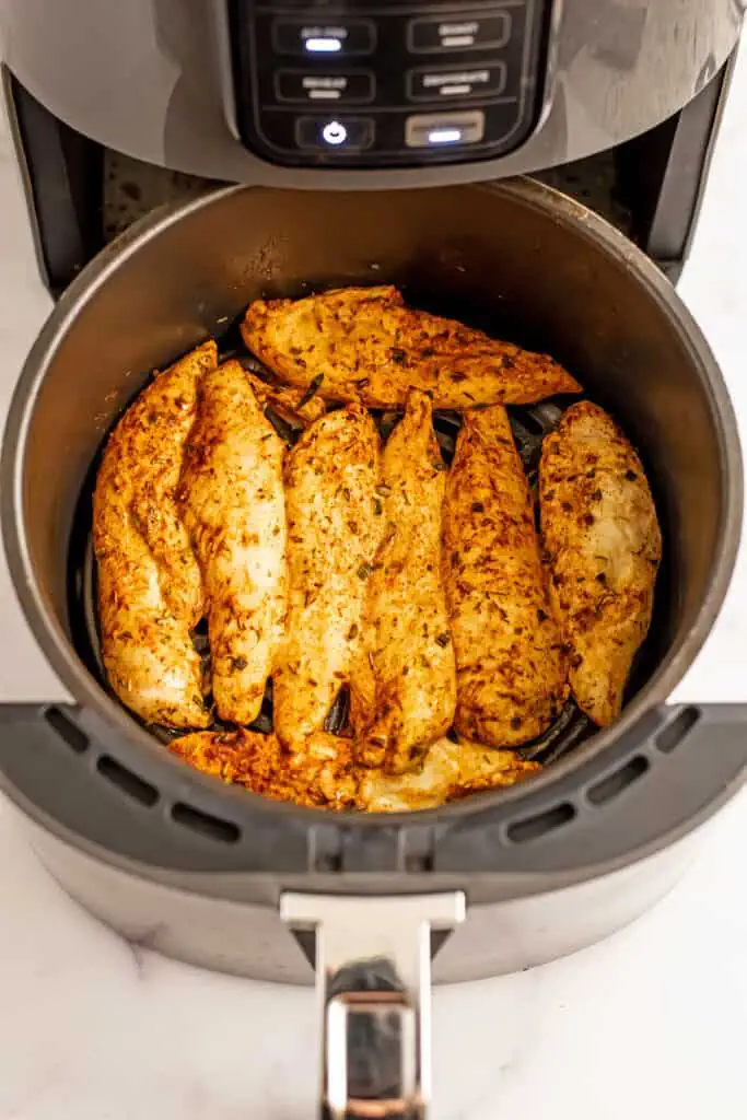 Chicken tenders in air fryer basket before being flipped.