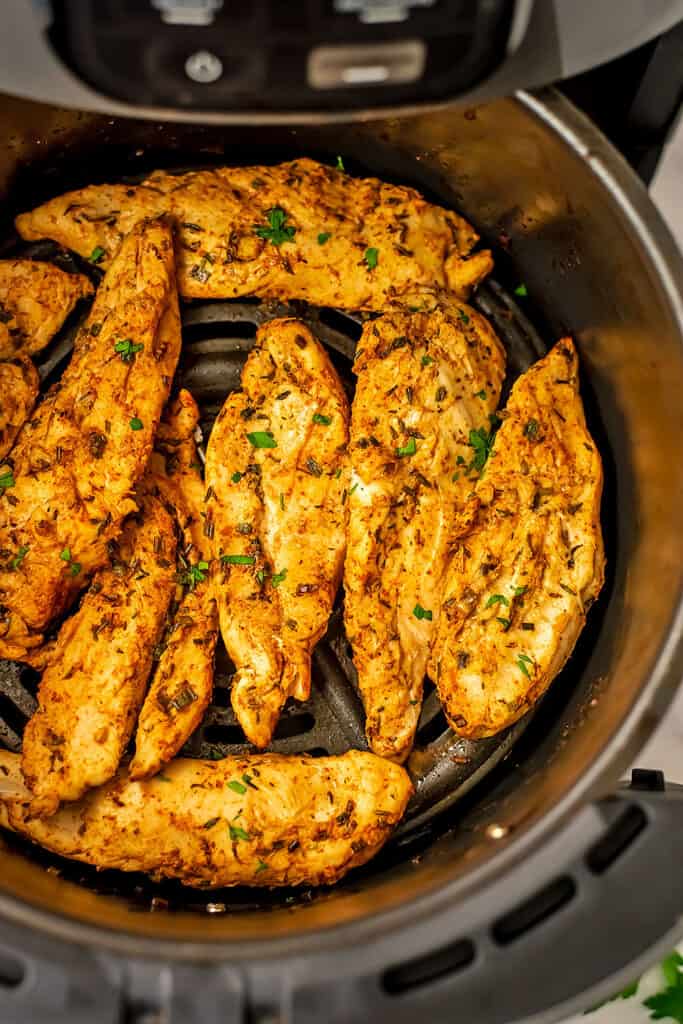 Grilled chicken tenderloins in the air fryer basket.