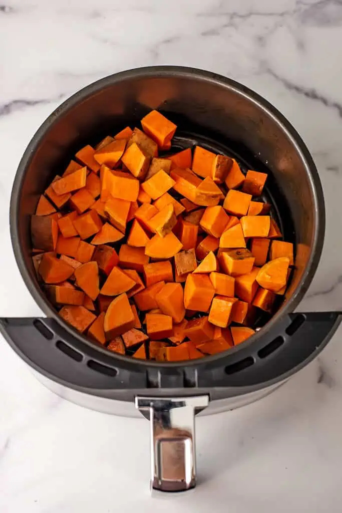 Sweet potato cubes in air fryer before roasting.