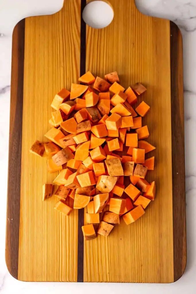 Sweet potato cubes on wood cutting board.