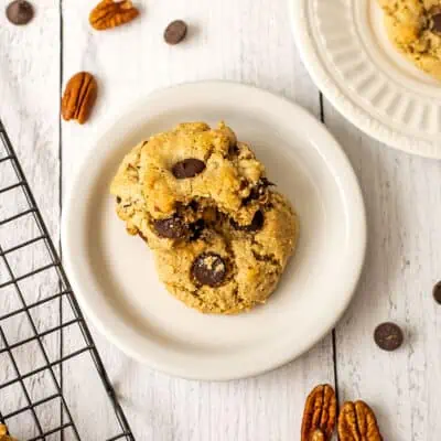 Two cookies on a white plate, one cookie has a bite taken.