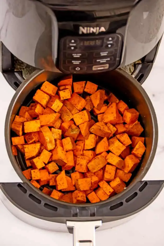 Sweet potato cubes in air fryer basket before cooking.