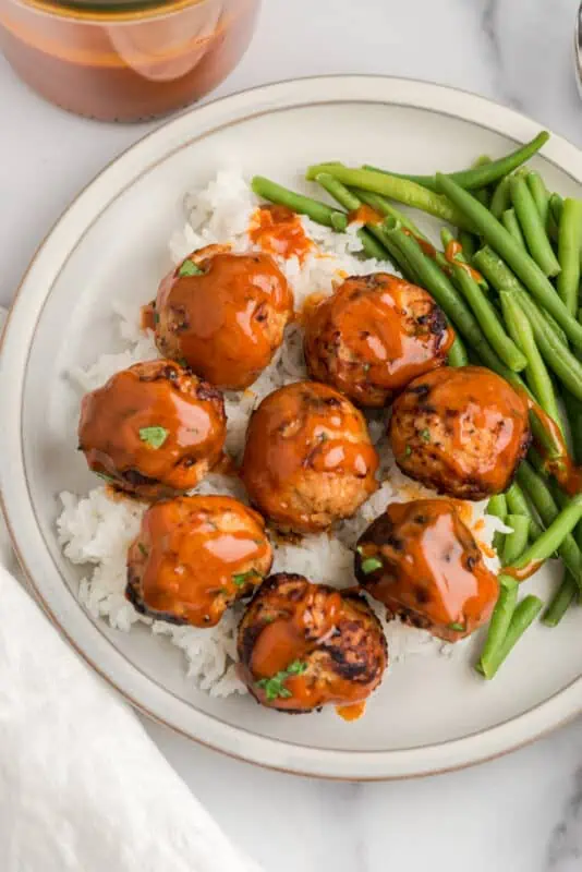Air fryer turkey meatballs on bed of rice with green beans on the plate.