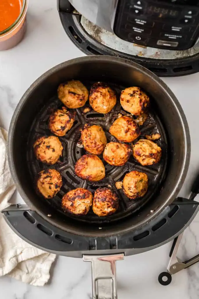 Ground turkey meatballs in air fryer basket after cooking.