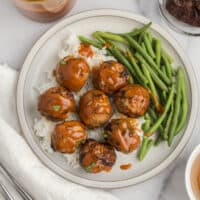 White plate with green beans, rice and air fryer turkey meatballs.