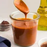 Large jar of honey chipotle sauce with spoonful of sauce dripping into jar.