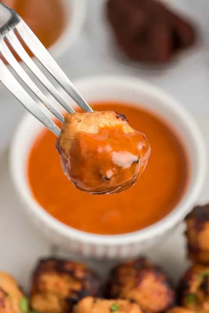 Air fryer turkey meatball on a fork dipped in honey chipotle sauce.
