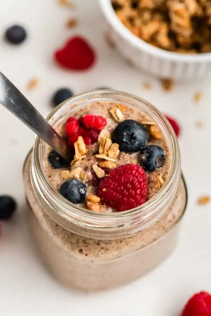 Flax pudding in glass jar with mixed berries and granola on top.