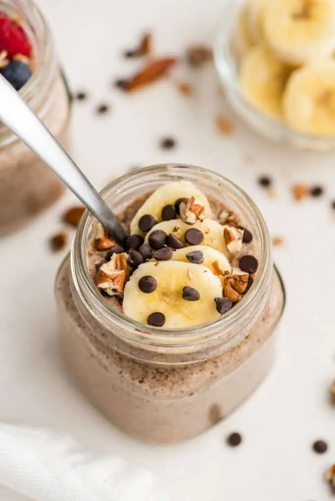 Flax pudding with bananas and chocolate on top with spoon in cup.