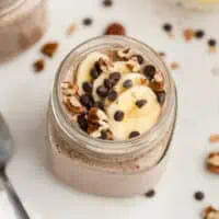 Flaxseed pudding in a glass with sliced banana and chocolate chips on top.