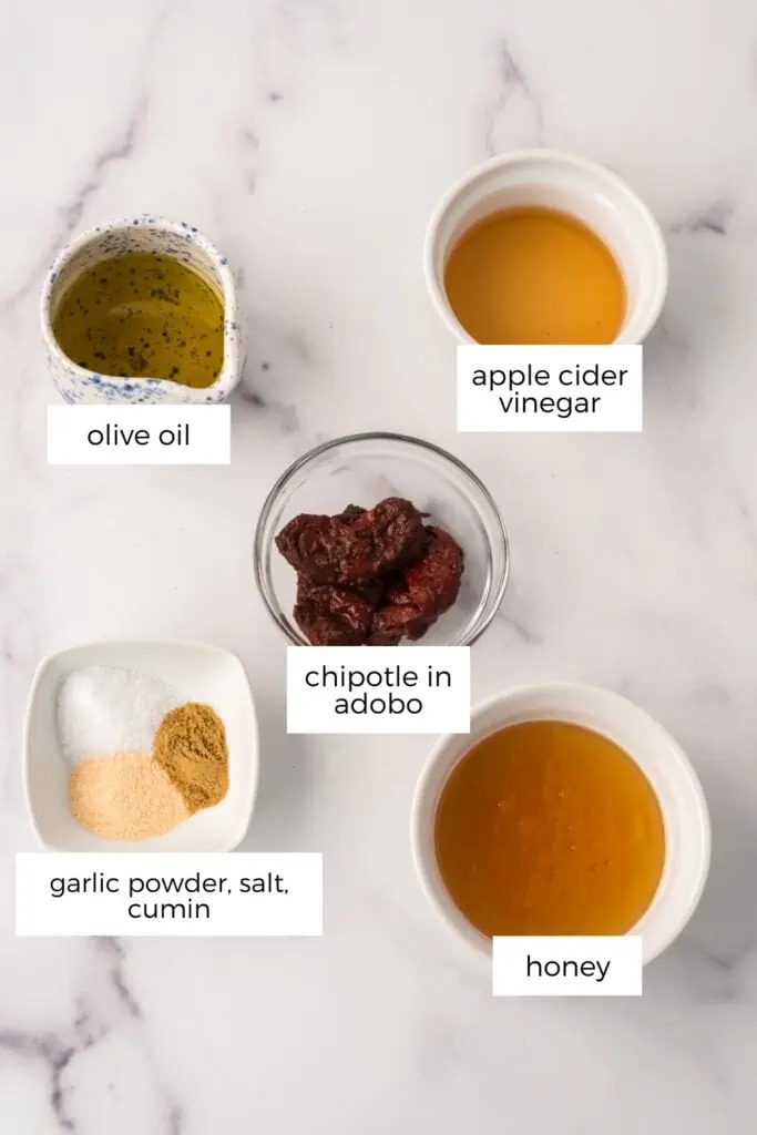 Chipotle honey sauce ingredients in ramekins on marble countertop.