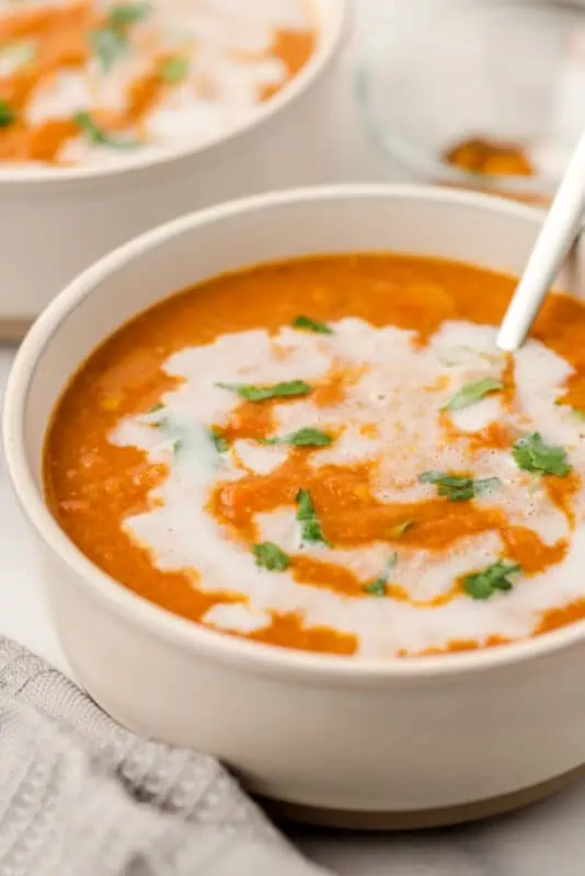 Bowl filled with Moroccan lentil soup with coconut milk on top.