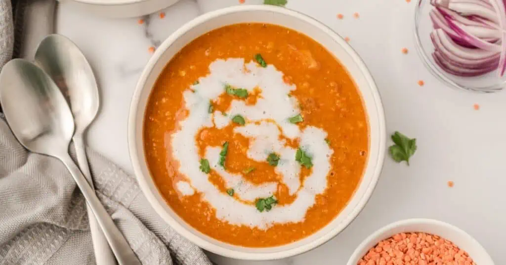 Moroccan red lentil soup with coconut milk drizzled on top.