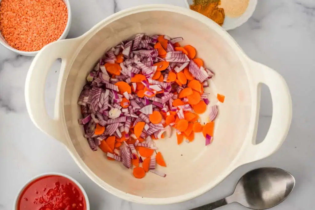 Red onion and carrots in a white pot before cooking.