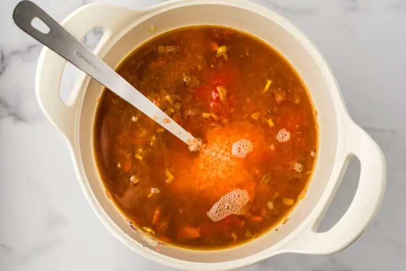 Lentils, tomatoes and vegetable broth added to pot before boiling.