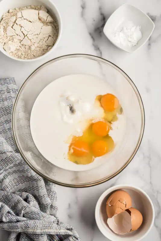 Liquid ingredients and eggs in glass bowl.