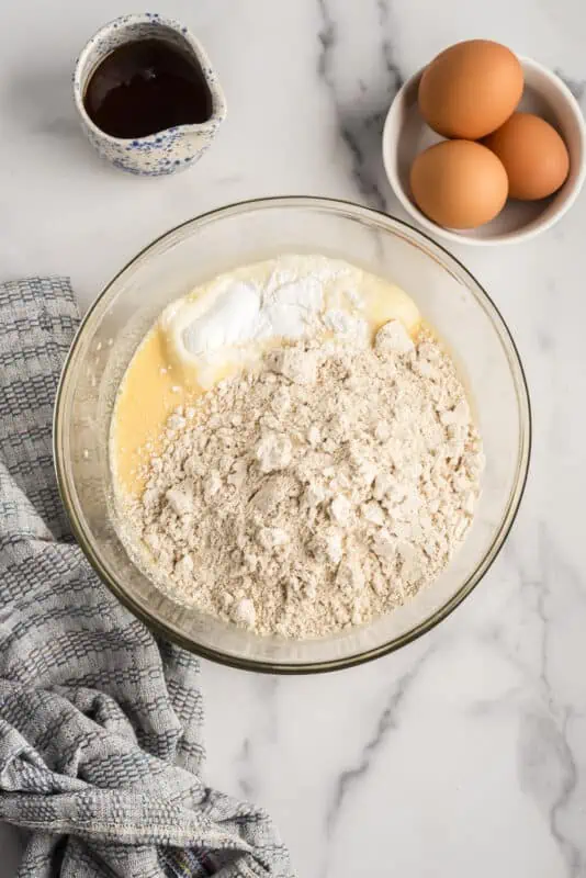 Dry ingredients added to the wet ingredients in a glass bowl.