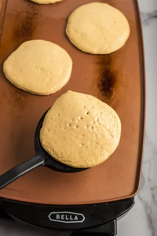 Spatula flipping pancake on skillet.