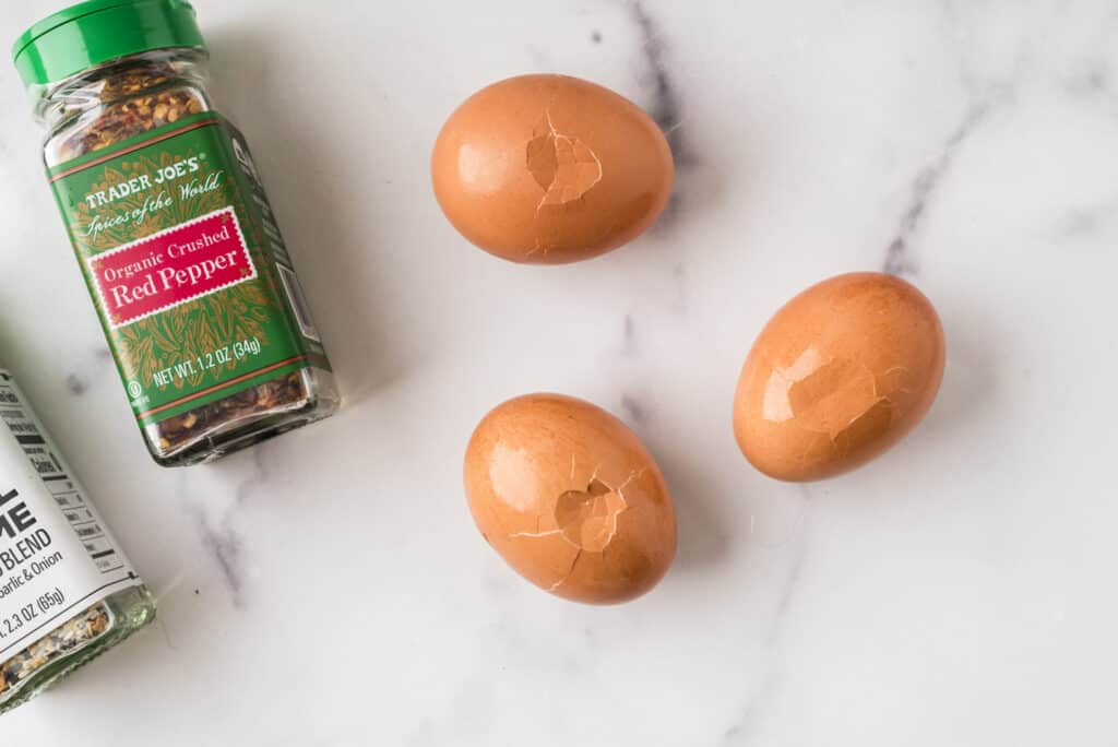 Hard boiled eggs with shell cracked on marble countertop.