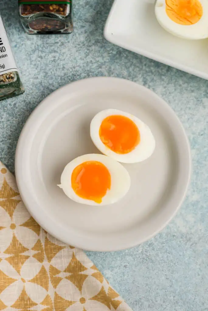 Hard boiled eggs with runny yolk on white plate.