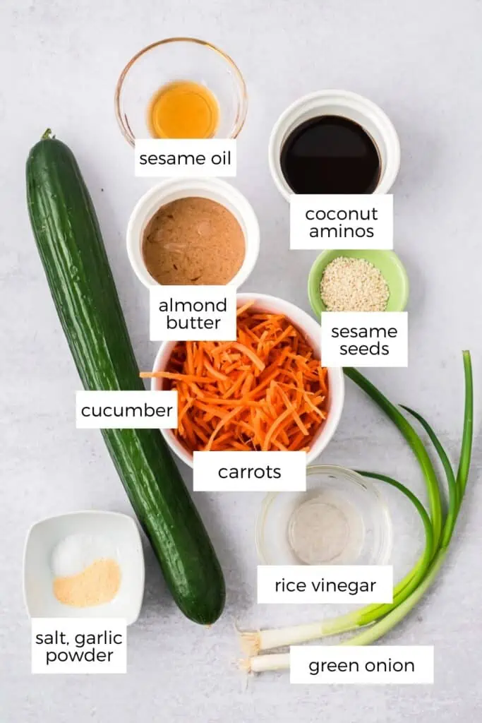 Ingredients to make cucumber carrot salad on cement countertop.