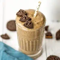 Protein cookie smoothie in a glass with a straw in the smoothie.