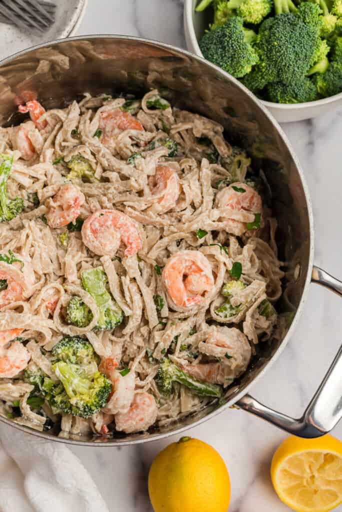Lemon broccoli and shrimp pasta in a pot with lemons on the side.