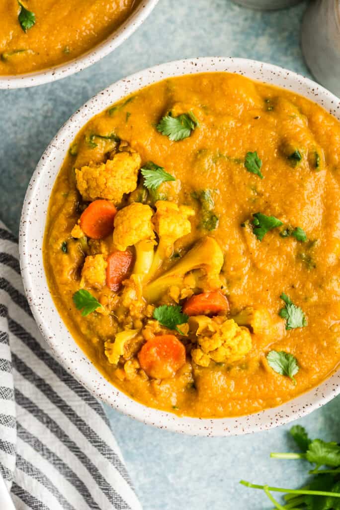 Cauliflower and carrots on top of creamy cauliflower and lentil soup in bowl.