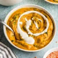 Bowl of cauliflower red lentil soup with a swirl of cashew cream in the bowl.