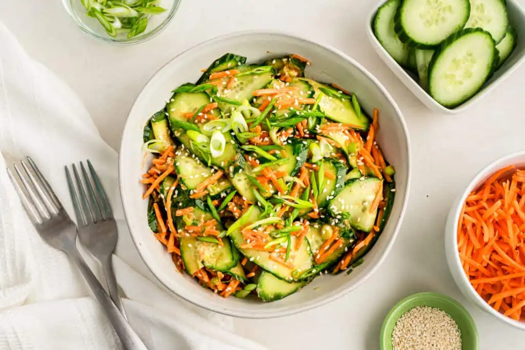 Asian carrot cucumber salad in white bowl with fork on the side.