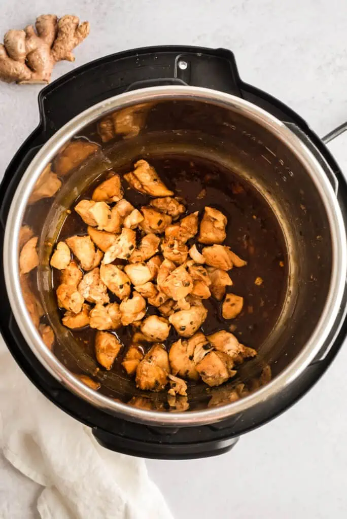 Cubed chicken added to teriyaki sauce in instant pot.