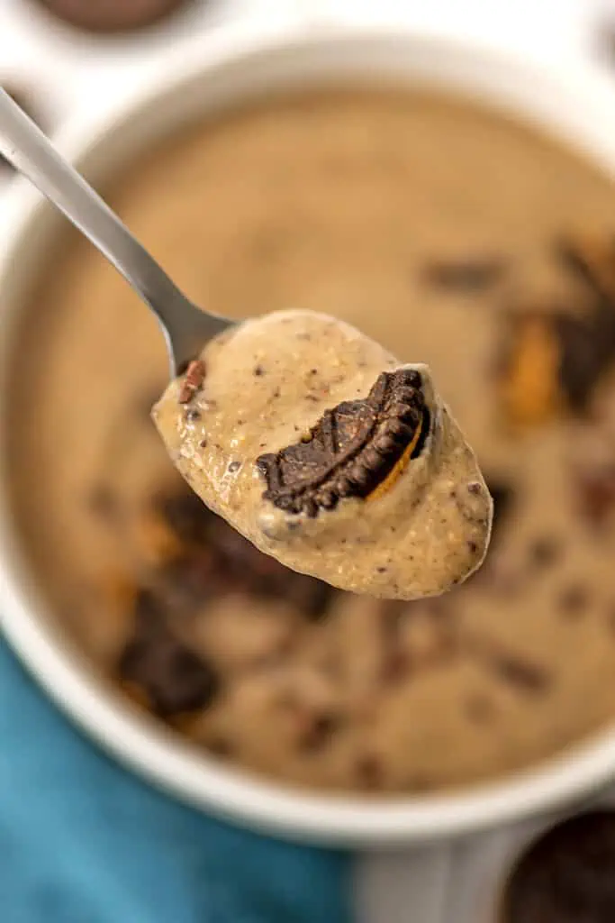 Spoonful of cookies and cream protein smoothie over bowl.