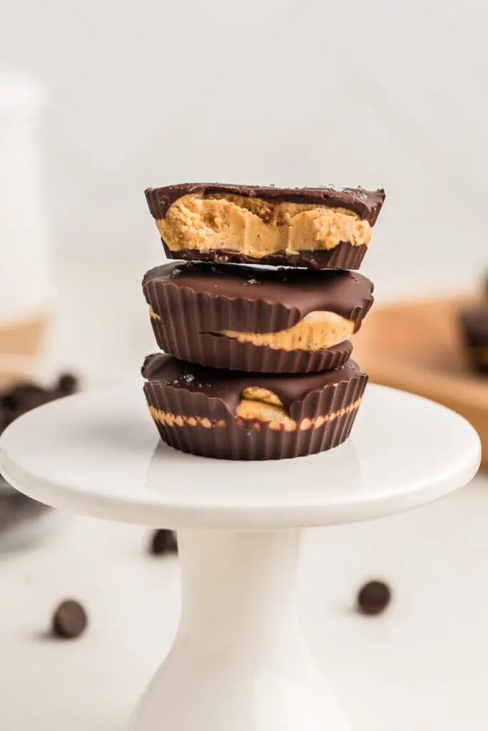 Three peanut butter cups stacked, one bite taken out of the peanut butter cup.
