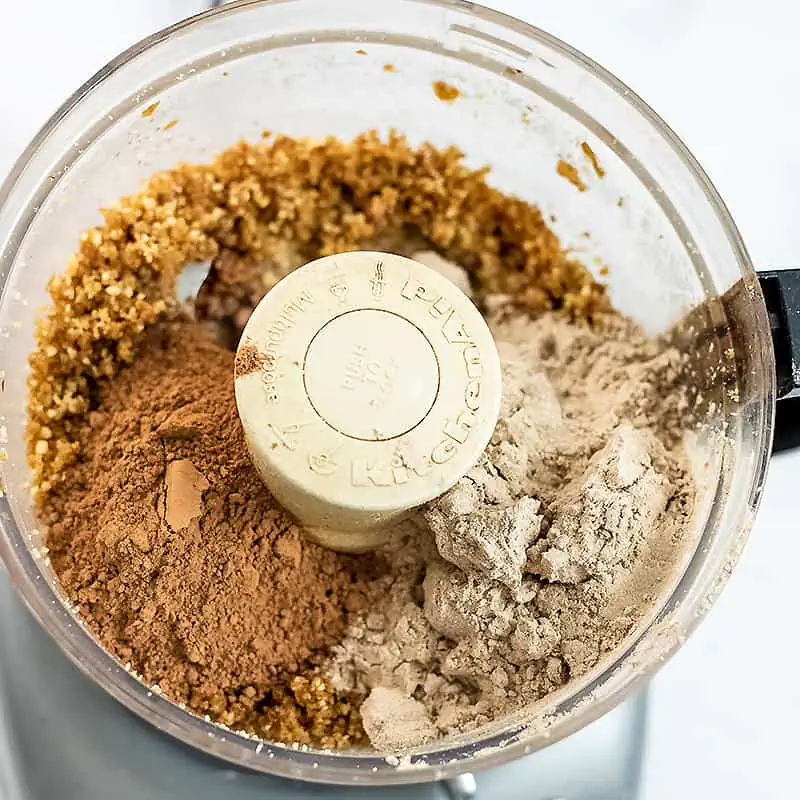 Cacao powder and protein powder added to food processor with date mixture.