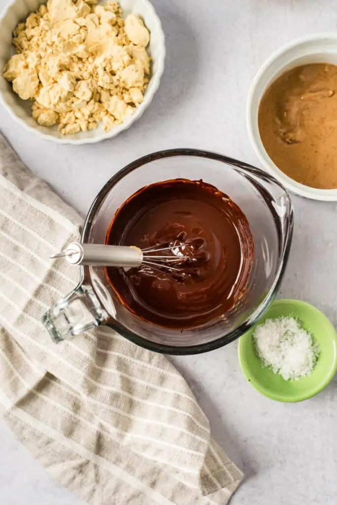 Melted chocolate in a glass measuring cup with a whisk resting in the cup.