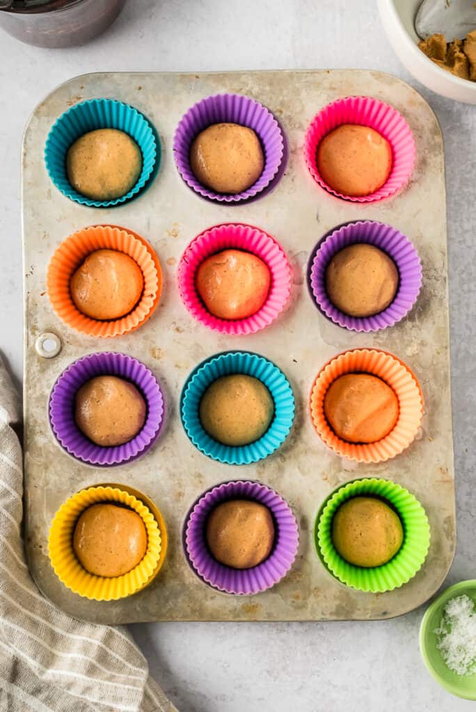 Protein peanut butter filling on melted chocolate in muffin tin.