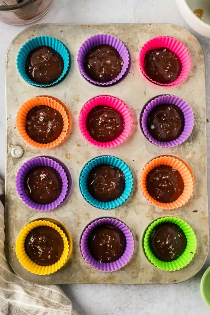 Peanut butter protein cups with flaky salt on top before freezing.