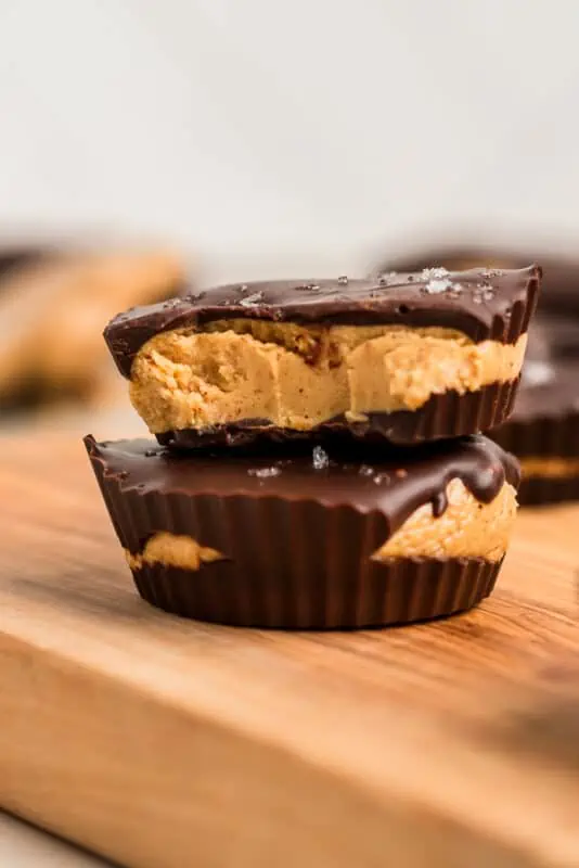 Protein peanut butter cups with a bite taken out of the cup stacked on top.