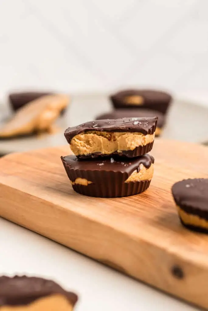Two peanut butter protein cups on a wood cutting board.
