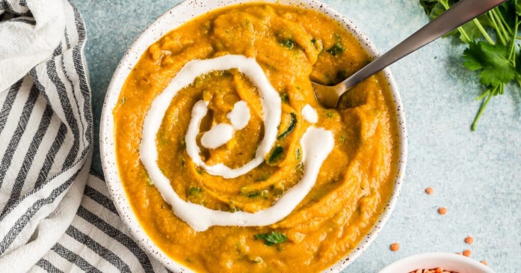 Bowl of cauliflower red lentil soup with a swirl of cashew cream in the bowl.