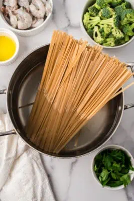 Fettucine noodles added to pot of boiling water.