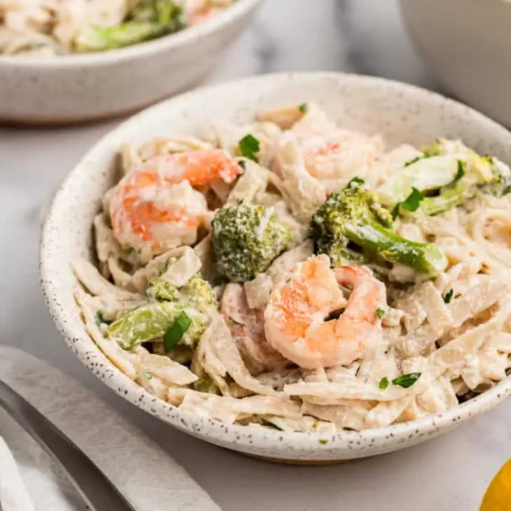 Creamy dairy free shrimp pasta in a bowl with white napkin on the side.