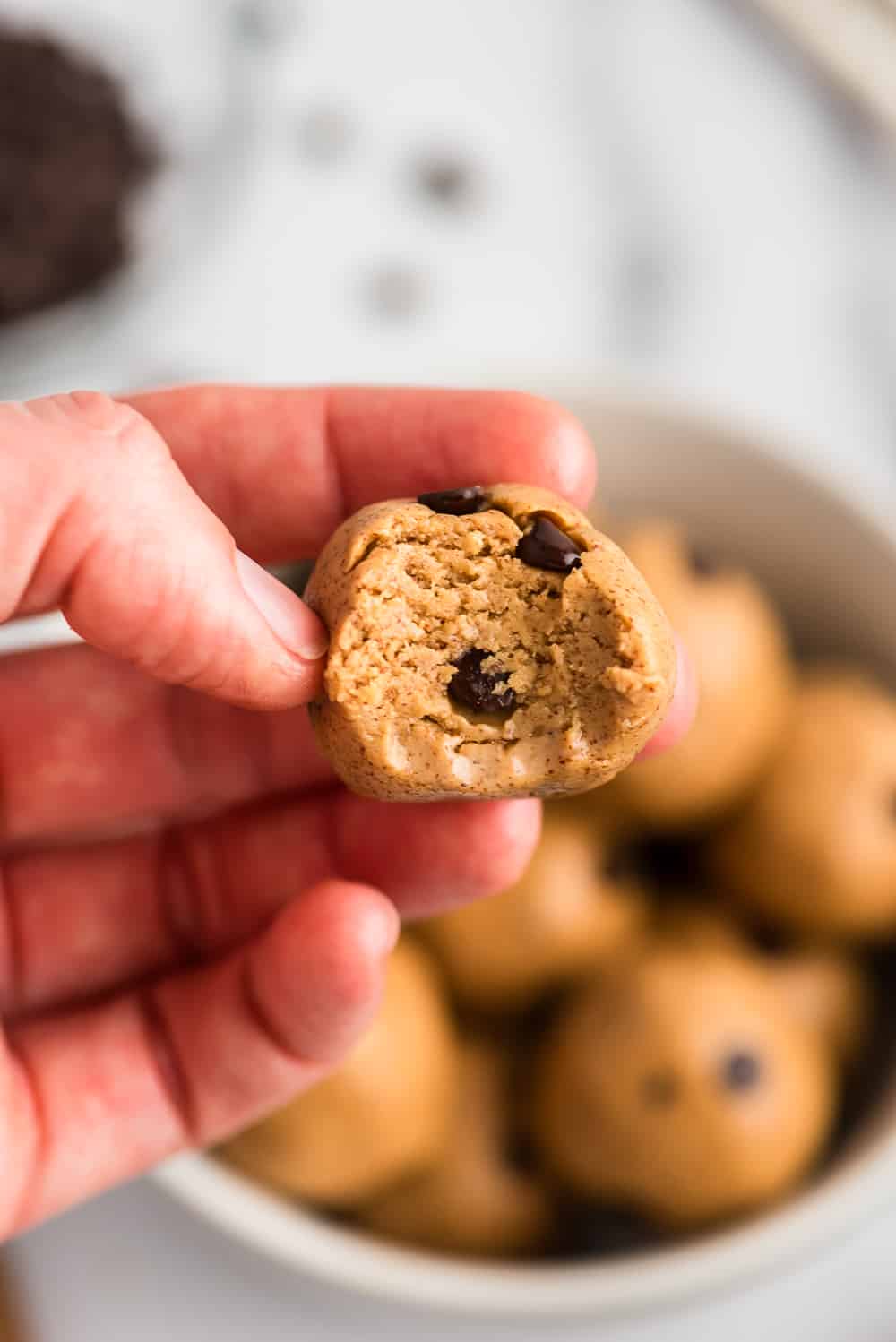 Hand holding protein almond butter balls with a bite taken out.